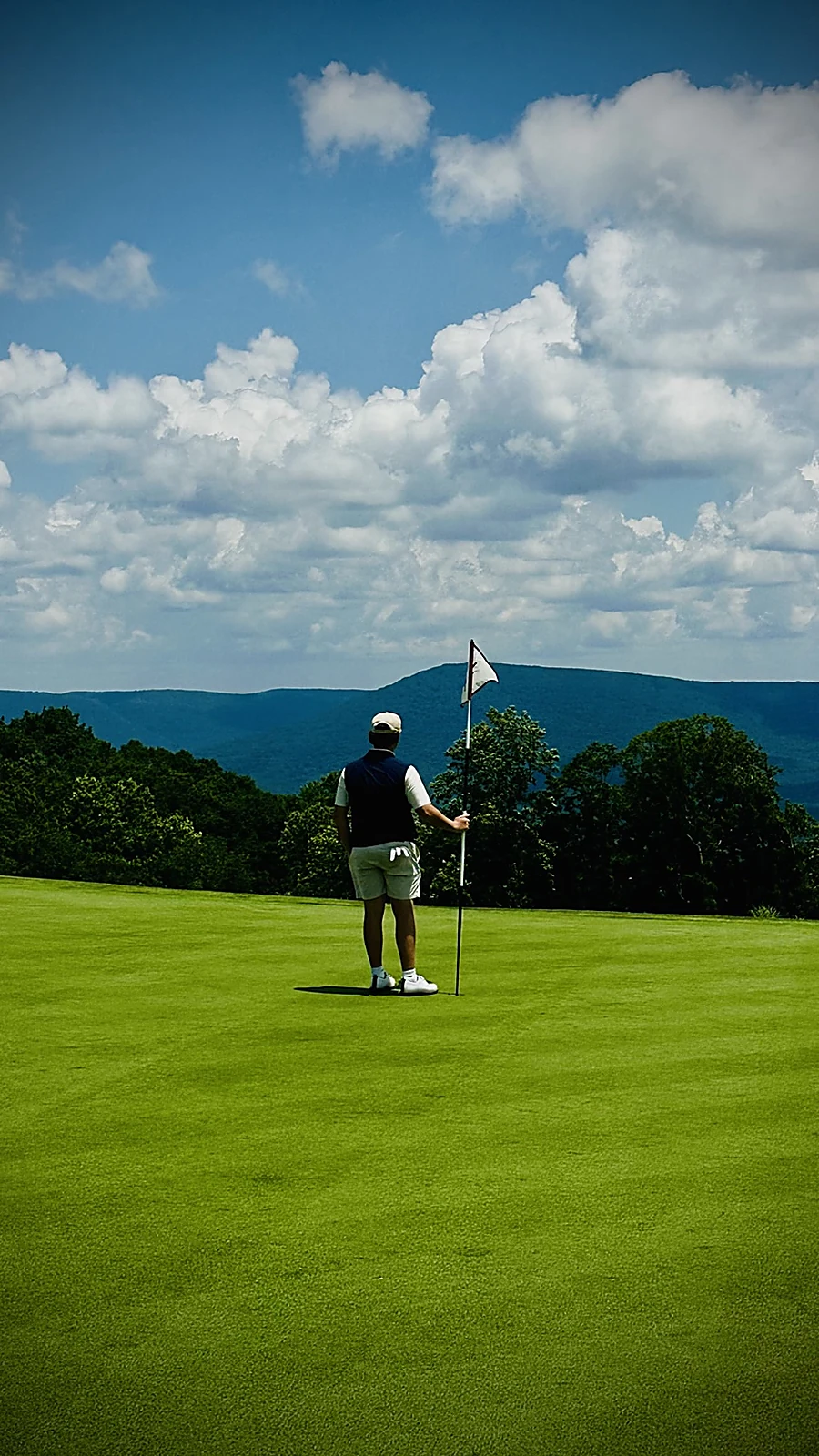 Will Martiny standing on a mountain golf green beside the flagstick