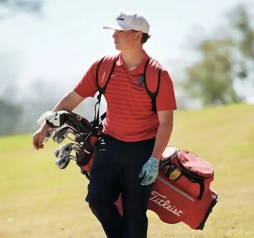 Will Martiny carrying a red golf bag during competition